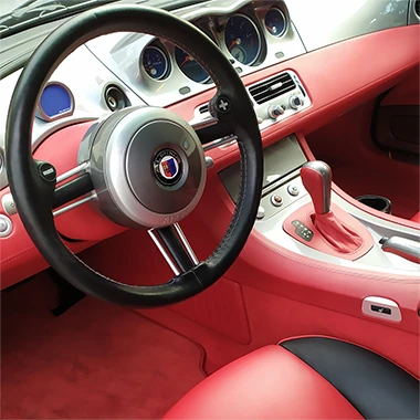 Kierownica, deska rozdzielcza oraz czerwona tapicerka we wnętrzu samochodu
